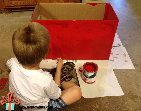 Ребенок красит картонную коробку